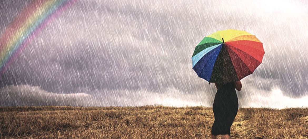 Une femme avec un parapluie marche sous la pluie dans un champ
