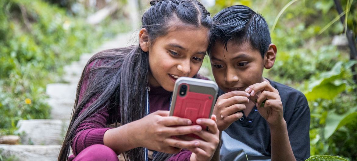 Deux enfants s'amusent pendant que leurs parents participent à un atelier sur la sécurité en ligne et l'éducation au Guatémala