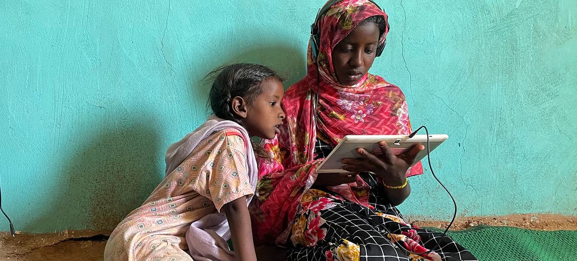 Des filles utilisent une tablette alimentée par l'énergie solaire dans un centre d'apprentissage en ligne à Jabalain, au Soudan.