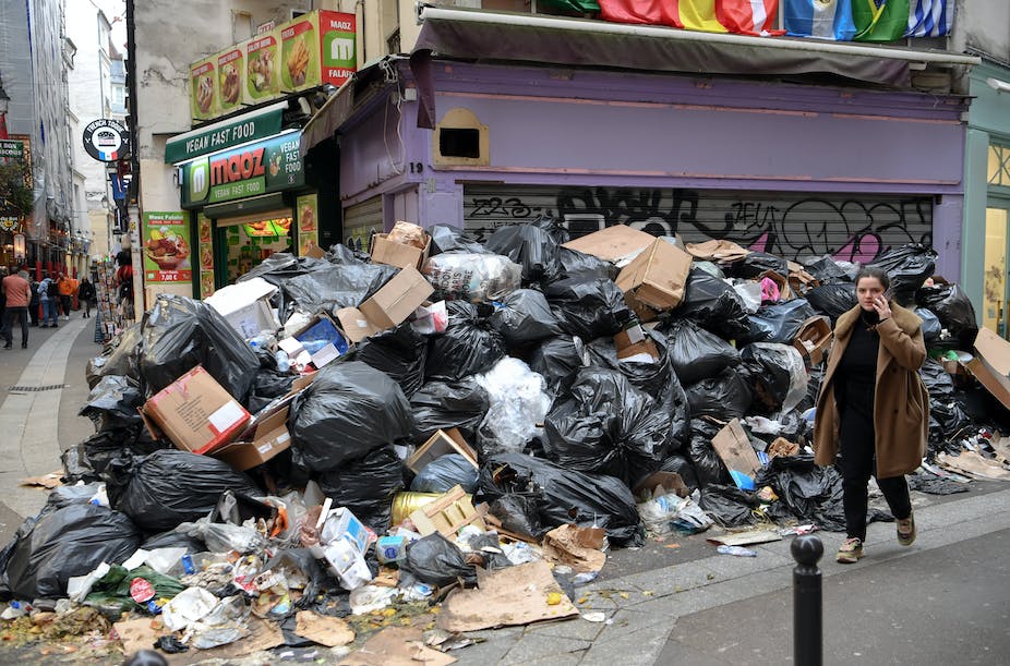 Des piétons passent devant des poubelles pleines dans le 5e arrondissement de Paris, alors que les éboueurs font grève contre les réformes des retraites, laissant de nombreuses rues de la capitale emplies de déchets nauséabonds, le 17 mars 2023.
