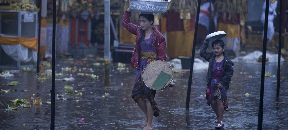 Une mère et sa fille essaient de se protéger de la pluie alors qu'elles traversent un marché.