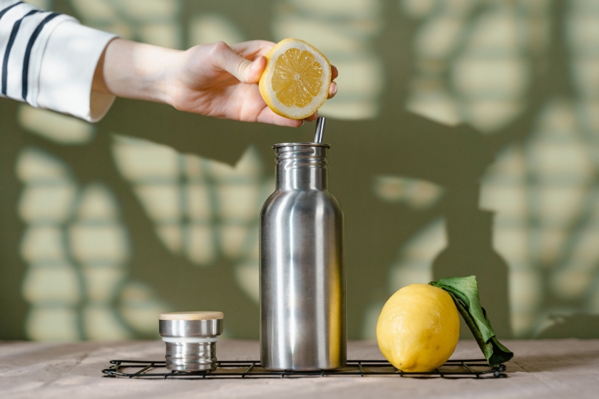 Squeezing a lemon over a reusable steel water bottle.