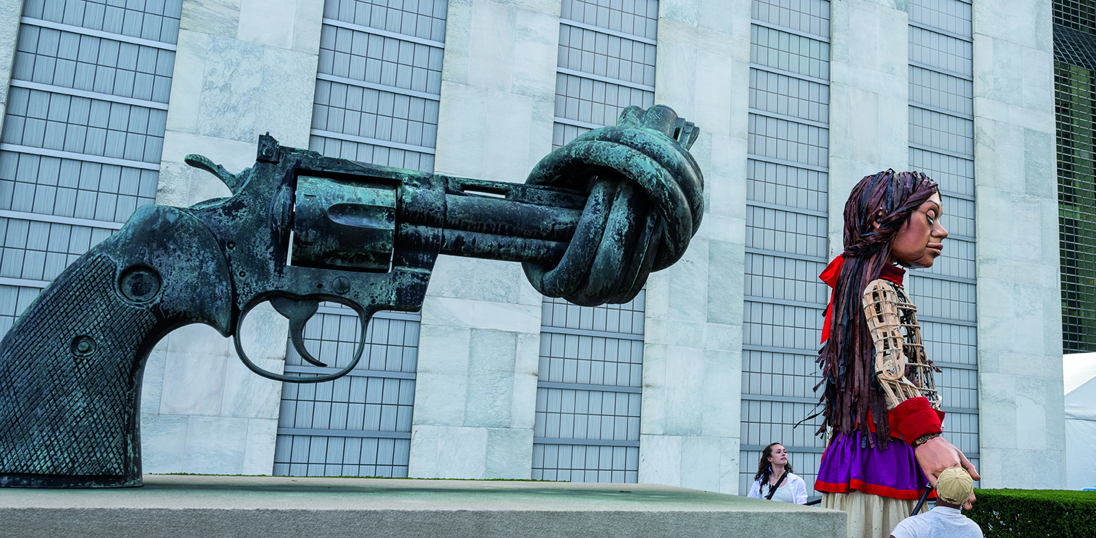 Une sculpture en forme de pistolet noué et une grande marionnette représentant une jeune fille, au Siège des Nations Unies.