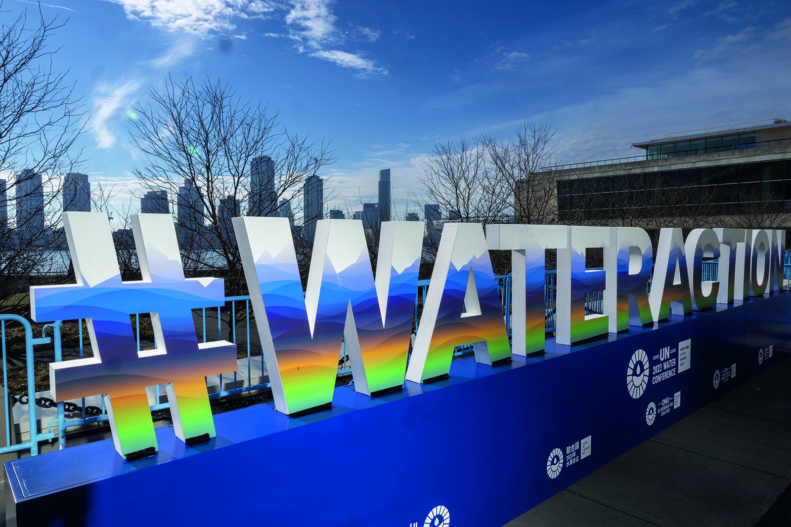 Vue panoramique d'un panneau multicolore affichant le hashtag 'eau' sur fond de paysage urbain