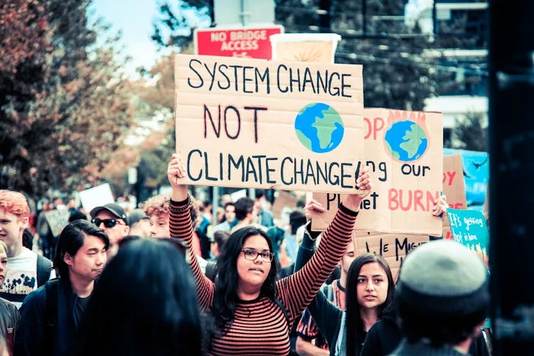 Manifestation où l’on peut voir une pancarte : System change not climate change.